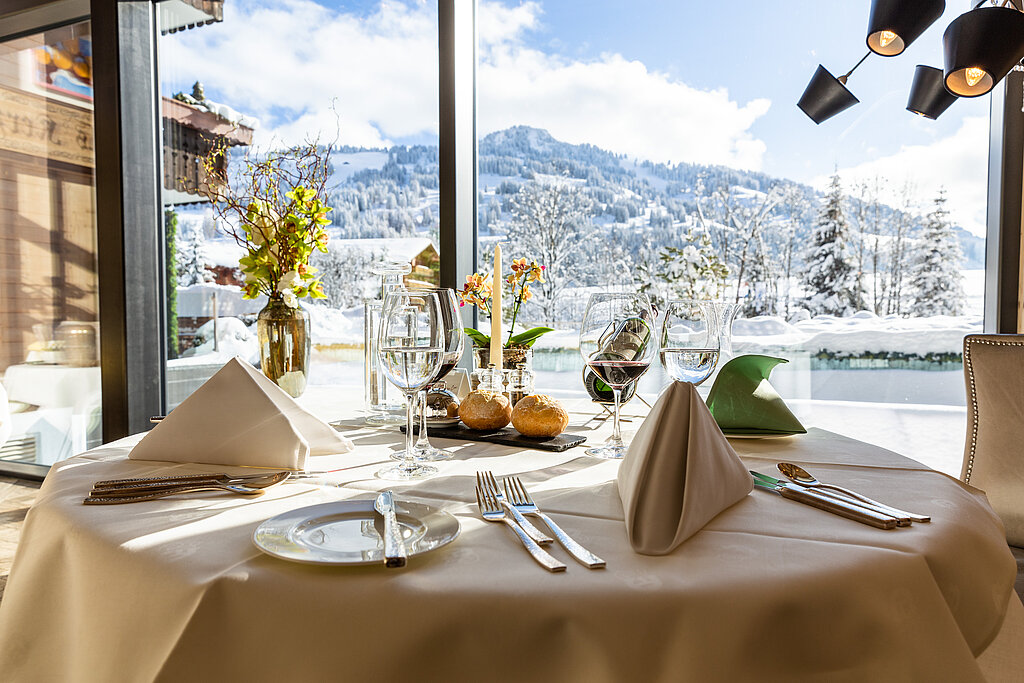 <p>Gedeckter Tisch im Hotel Ermitage mit Blick auf den aussen Pool und auf das verschneite Horneggli.</p>
