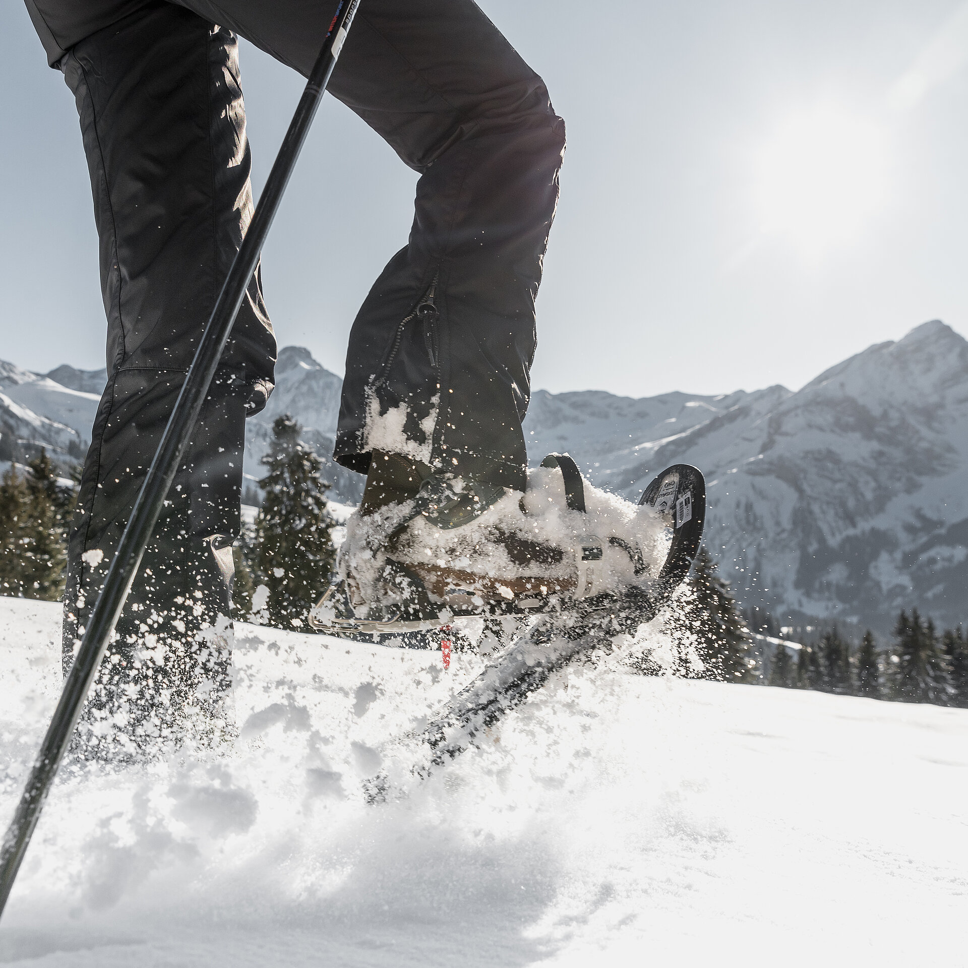 <p>Männliche Beine welche mit Schneeschuhschuhen durch den Schnee stampfen vor herrlicher Bergkulisse.</p>