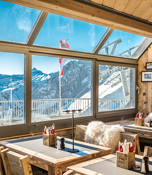 <p>Tisch und Stühle im Bergrestaurant La Videmanette mit Blick auf eine verschneite Berglandschaft.</p>