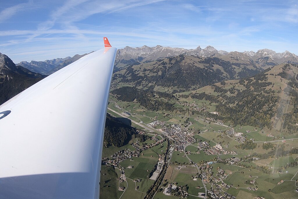 <p>Aussicht von einem weissen Flugzeug auf das grüne und bergige Saanenland.</p>