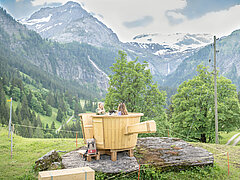 Grosses Fondue Caquelon aus Holz auf einem Hügel vor einer Bergkulisse.