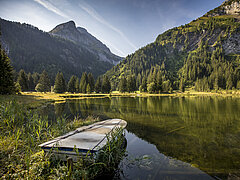 Le Lauenensee en automne avec les montagnes en arrière-plan. Au premier plan flotte encore une barque.