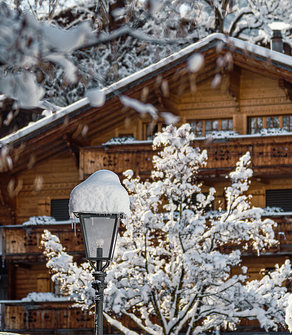 A typical four-storey wooden chalet with balconies amid snow-covered trees.