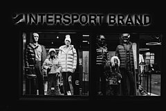 Ein Schaufenster von Intersport mit mehreren Schaufensterpuppen in Winterbekleidung. Die Modelle tragen Jacken, Mützen und Skiausrüstung.