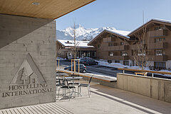 Entrance to a youth hostel with a view of snow-covered mountains.