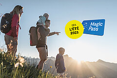 Une femme, un homme et deux enfants dans une prairie verdoyante. En arrière-plan, des montagnes et un coucher de soleil. Logo Magic Pass bleu et blanc et bouton jaune "dès l'été 2025".