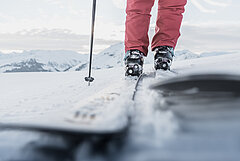 Nahaufnahme von Ski, im Hintergrund die Skipiste und verschneite Bergen.