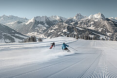 Two skiers enjoy the descent from Horneggli on a freshly groomed slope.