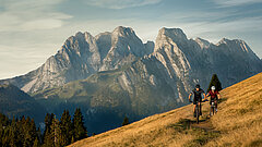 Mountainbiker am Trail mit beeindruckender Bergkette im Hintergrund