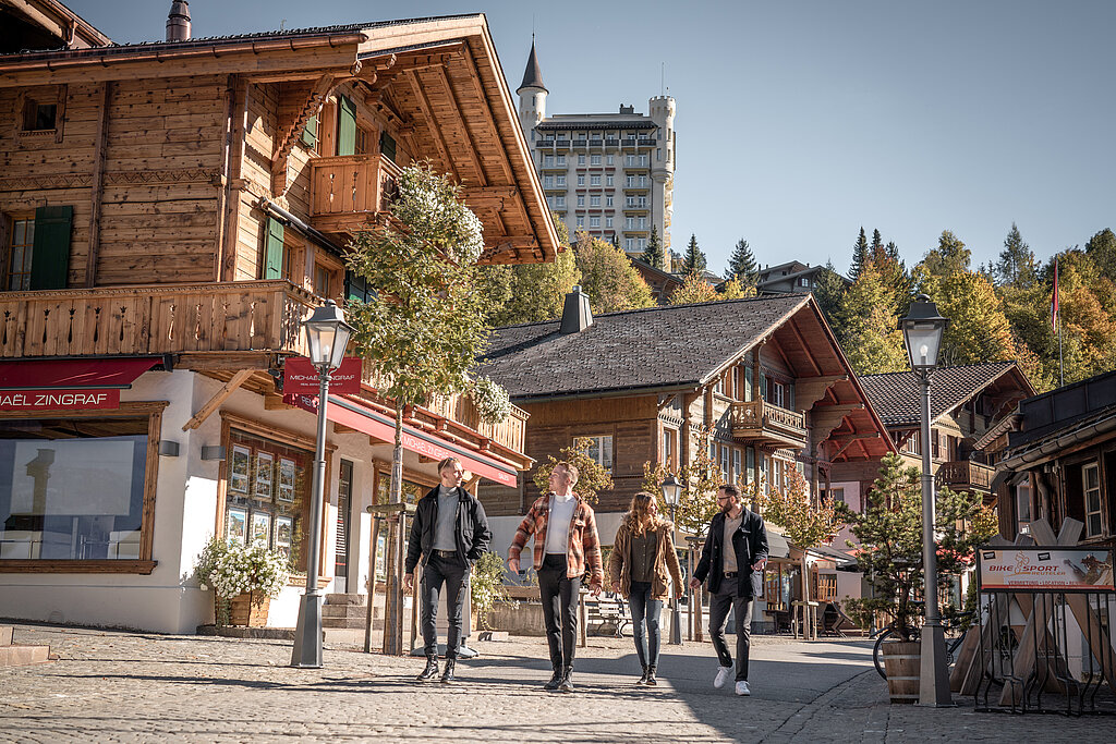 <p>Vier Personen gehen gemütlich durch die Promenade in Gstaad an einem schönen Herbsttag.</p>