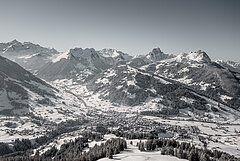 Panoramic view of the village of Gstaad in winter, with the Eggli and other mountains in the background.