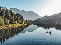 Deux personnes traversent le lac sur leurs stand up paddles au cœur d’un magnifique paysage de montagne.