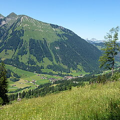 View of a green valley with a small village and many mountains.