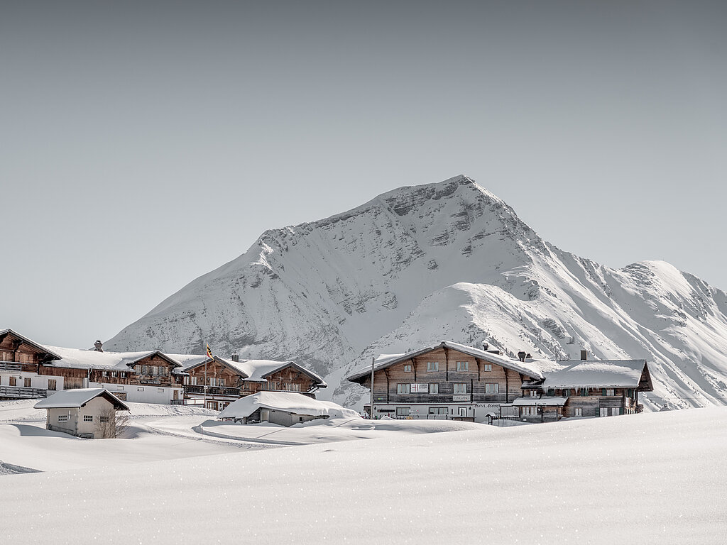 Schöne Winterlandschaft in weissen Bergen, im Vordergrund schneebedeckte Häuser mit Bergrestaurant.