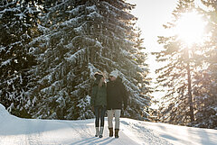 Zwei Personen wandern durch den verschneiten Wald