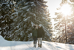 Zwei Personen wandern durch den verschneiten Wald