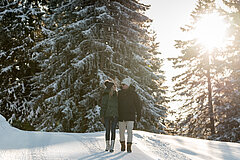 Zwei Personen wandern durch den verschneiten Wald