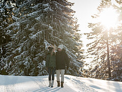 Zwei Personen wandern durch den verschneiten Wald
