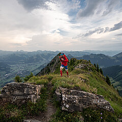 Person in red clothing running up the mountain on a hiking trail.