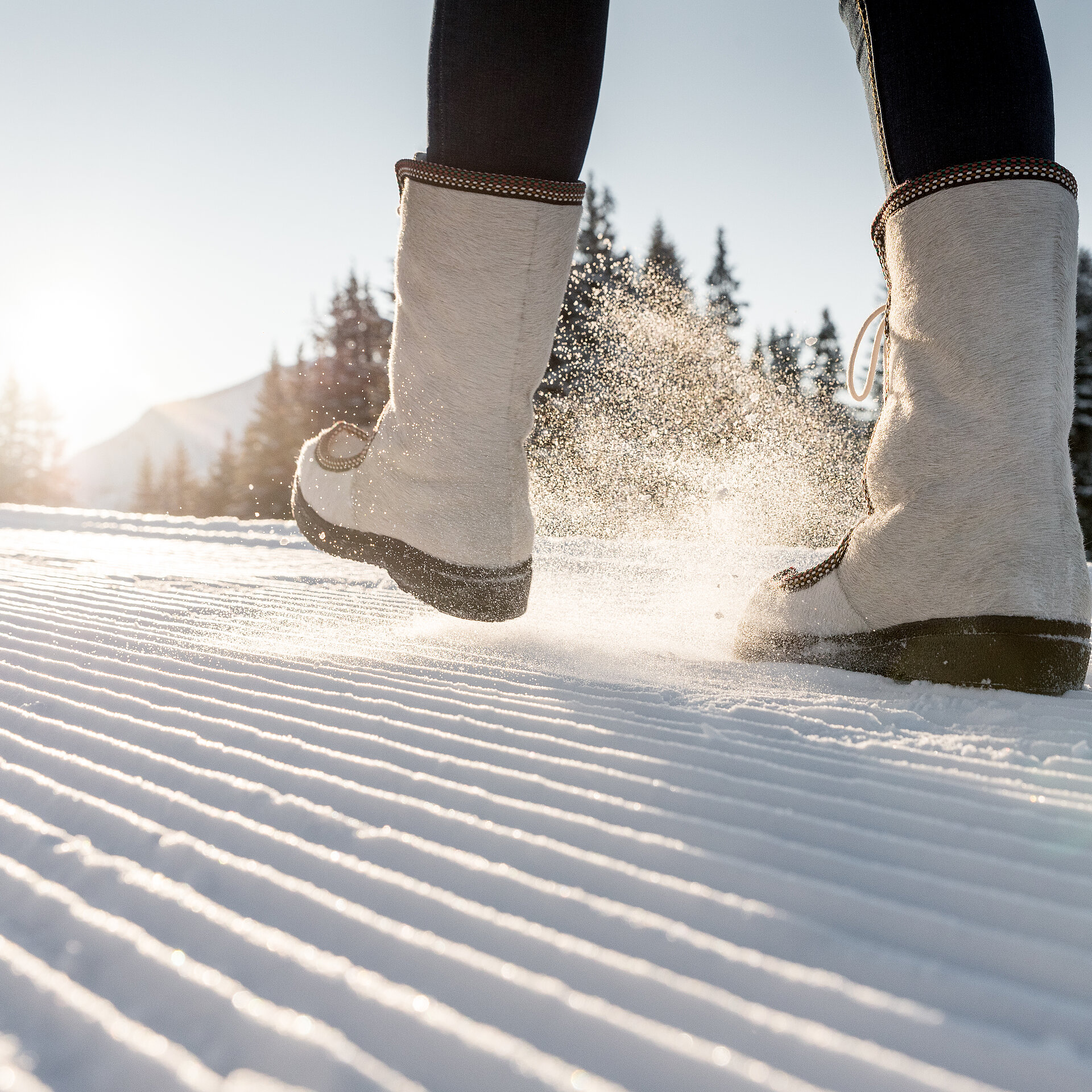 Detailansicht von Winterstiefeln auf frisch präpariertem Winterwanderweg.