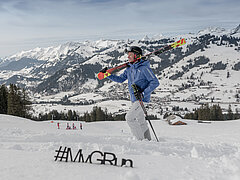 Former ski racer Mike von Grünigen in his ski gear against a wintry mountain backdrop.