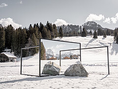 Kunstausstellung auf einer verschneiten Wiese mit Spiegeln und Steinen