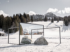 Kunstausstellung auf einer verschneiten Wiese mit Spiegeln und Steinen