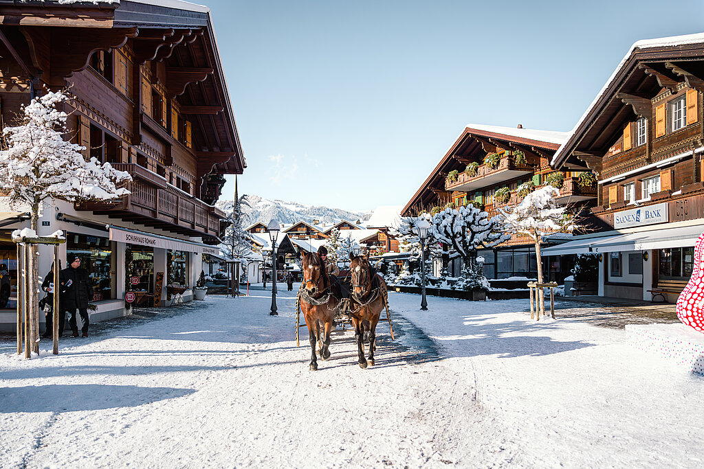 <p>Schneebedeckte Gstaader Promenade mit Blick auf die Chalet-Häuser und Pferdekutsche</p>