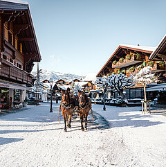 Schneebedeckte Gstaader Promenade mit Blick auf die Chalet-Häuser und Pferdekutsche