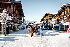 Promenade de Gstaad sous la neige avec vue sur les chalets et la calèche.