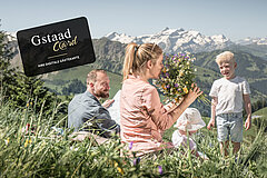 Familie sitzend auf Blumewiese mit Berge im Hintergrund