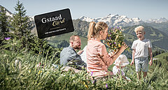 Familie sitzend auf Blumewiese mit Berge im Hintergrund