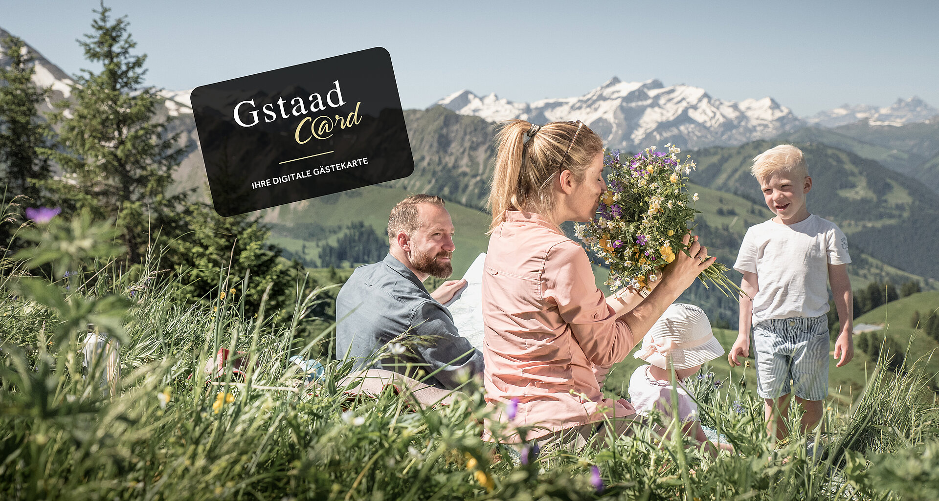 Familie sitzend auf Blumewiese mit Berge im Hintergrund