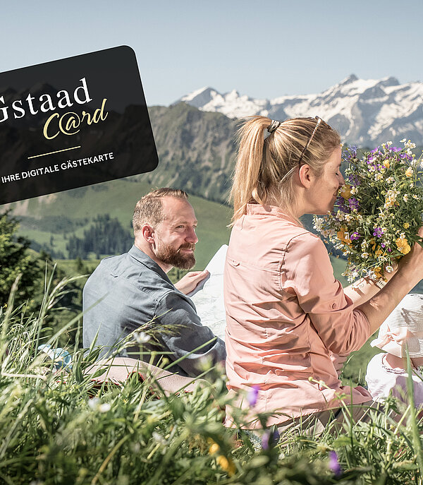 Familie sitzend auf Blumewiese mit Berge im Hintergrund