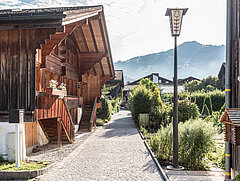 A small path leads past wooden chalets and green gardens.