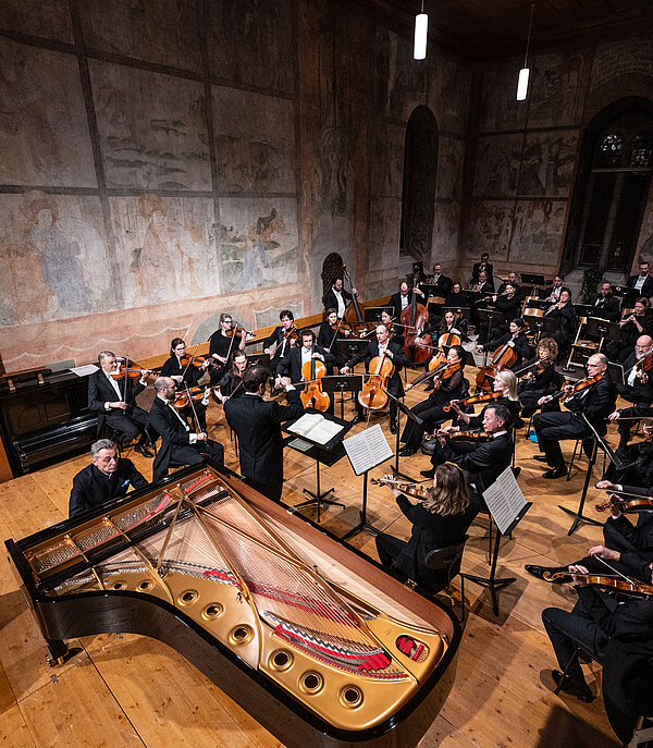 Sommets Musicaux de Gstaad Ein Orchester spielt klassische Musik in einer Kirche mit christlichen Sujets an den Wänden.