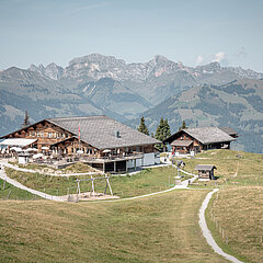 Mountain restaurant on Wispile in summer, surrounded by green meadows and overlooking the surrounding alpine mountain ranges.