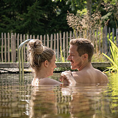 Eine Frau und ein Mann schwimmen im Outdoor-Pool im Maison Hornberg.
