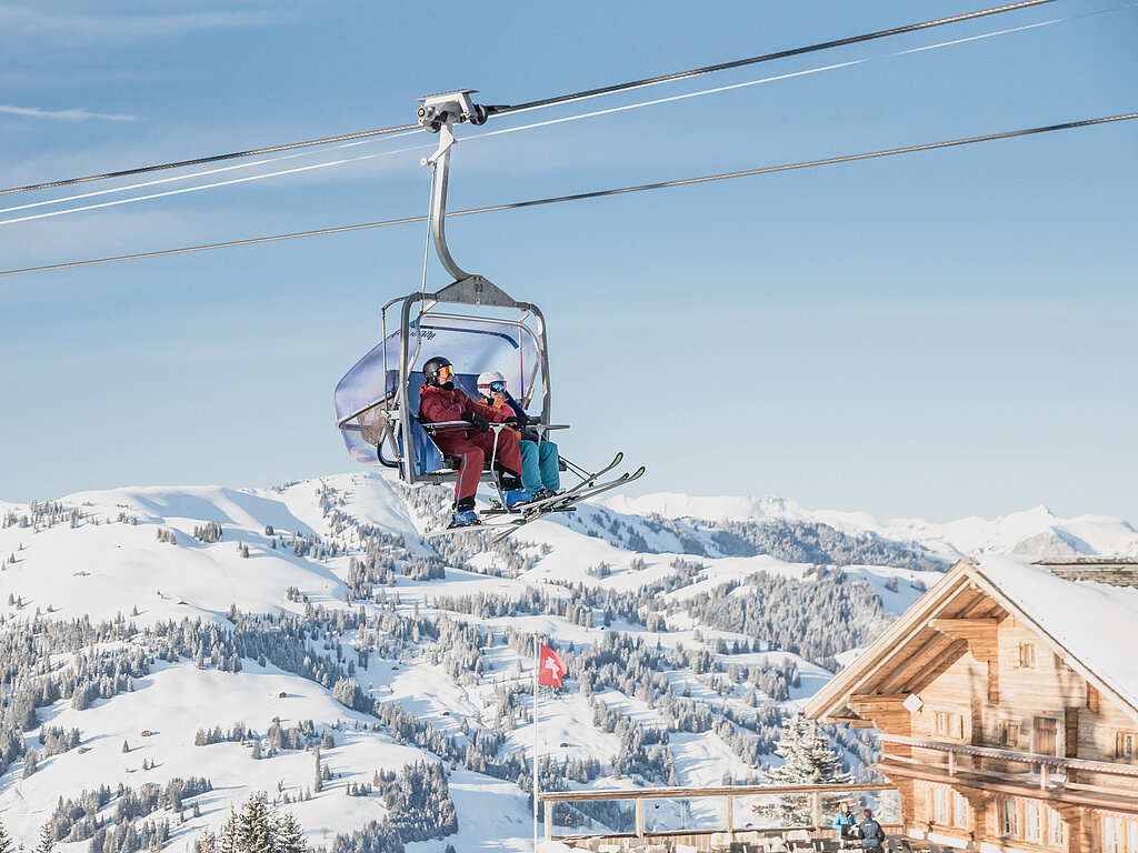 <p>Sessellift mit 2 Skifahrern und verschneiter Aussicht.&nbsp;</p>