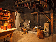 Alte Küche mit einem Kamin und einem hölzernen Tisch im Landschaftsmuseum in Saanen.