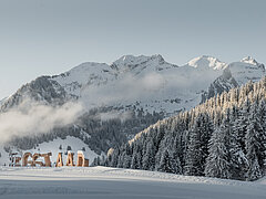  Snowy mountain backdrop with fir forest and wooden #Gstaad sign.