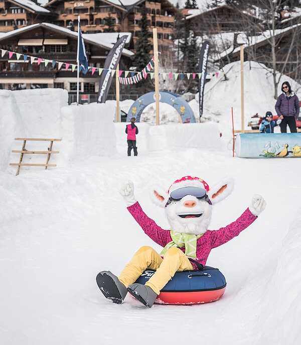 Saani, das Saanenland-Maskottchen rutscht auf einem Ring auf der Piste im Winterspielplatz Saanenmöser.