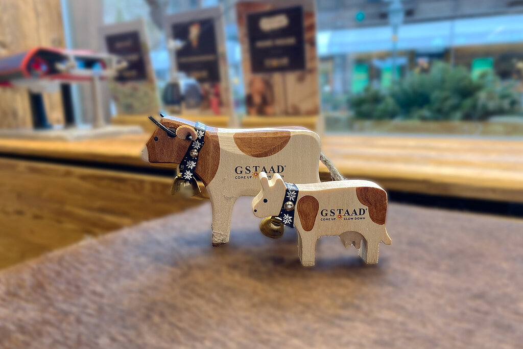 Kleine beige-braune geschnitzte Holz-Kühe mit Glocke und Gstaad-Logo