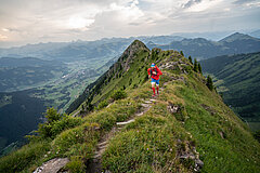 Un coureur de trail court sur une arête en direction du sommet.