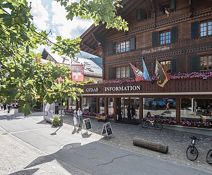 Ein typisches Schweizer Chalet mit touristischen Informationen. Draußen stehen Fahrräder und es blühen Blumen in den Fenstern.