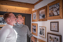 Deux hommes admirent différents tableaux dans une galerie à Gstaad.