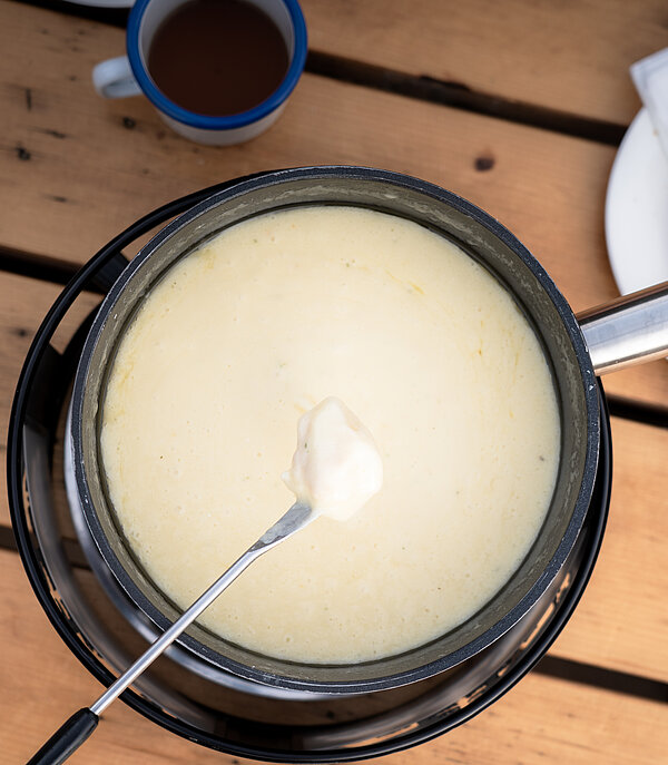 Käse Fondue auf einem Holztisch mit Brot.