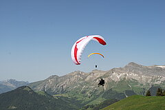 Parapente rouge et blanc décollant sur une montagne par une belle journée d'été.