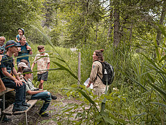 Une garde-faune raconte au groupe des informations intéressantes sur les plantes du Lauenensee dans une forêt.
