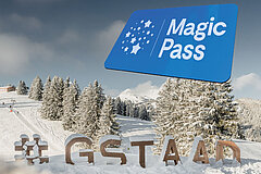 Winterlandschaft mit verschneiten Bäumen, Skipiste und Magic Pass Anzeige vor blauem Himmel.